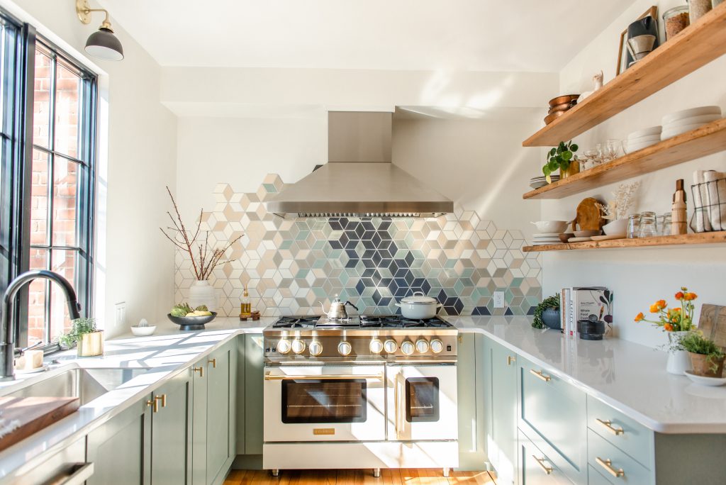 a white range underneath blue and green backsplash tiles.
