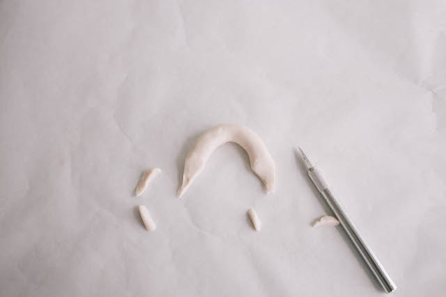 Roll clay into a five-inch log, and then form it into an arch shape. Cut the ends into points.