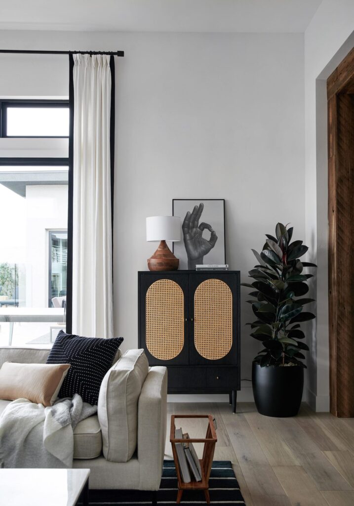 a living room with gray walls, a gray couch, and a black and wood accent table with a black-and-white photo of a hand and a wooden lamp.