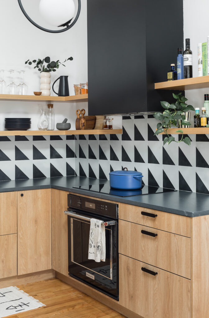 a side view of the kitchen's oven and hood, surrounded by lower cabinets and the open shelves.