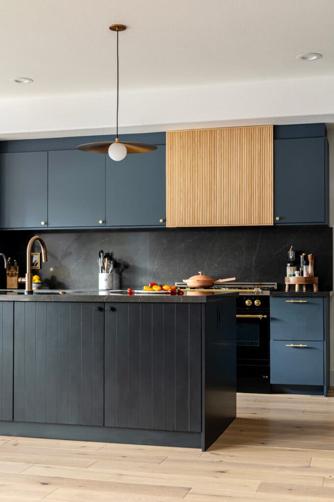 Black kitchen island with reeded hood and navy cabinets