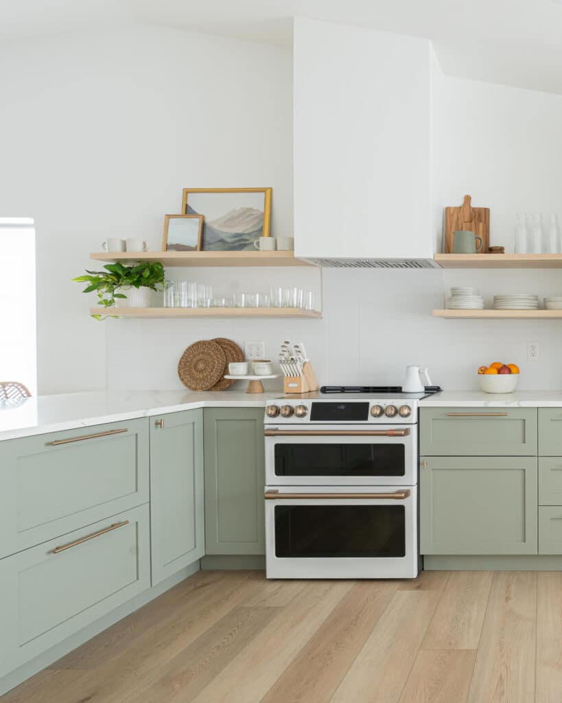 Sage green cabinets with white wall and open shelves