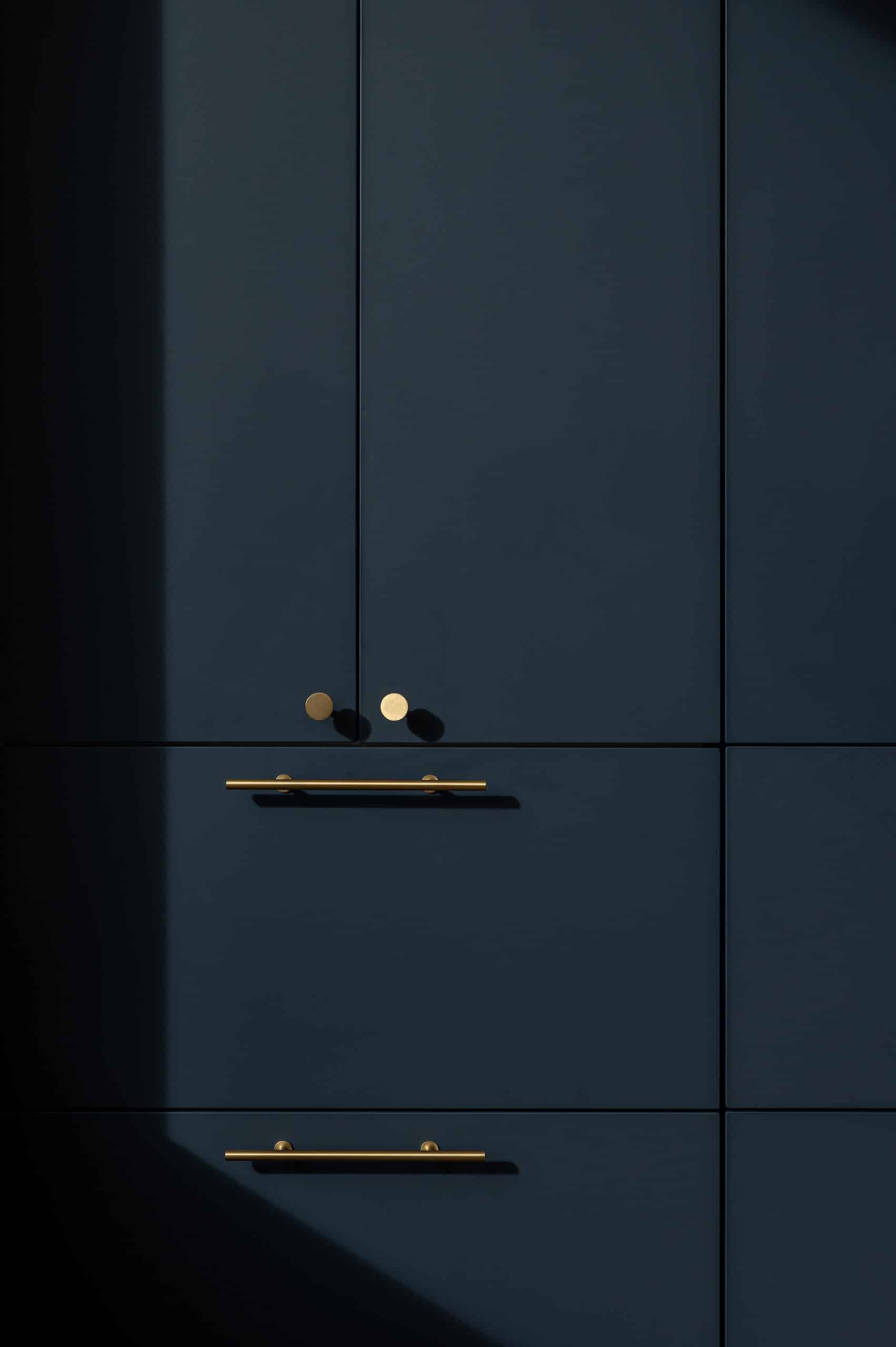 Navy blue kitchen cabinet closeup with brass hardware