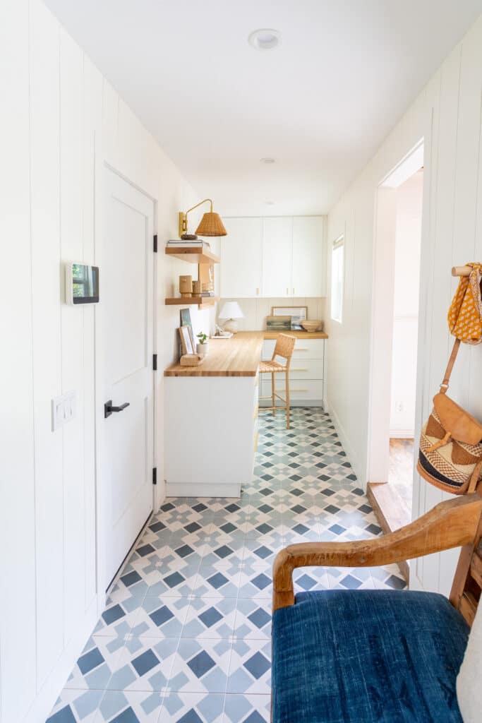 White shiplap walls with white cabinets and blue pattern tile